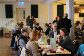 an Tischen sitzende und stehende Arbeitskreisteilnehmer Saalmitte