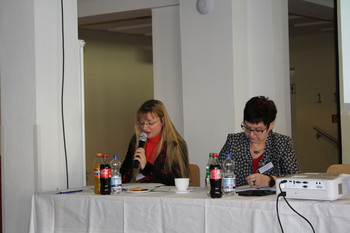 eine Rednerin mit weiterer Person auf Podium