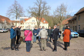 Gruppe von stehenden Personen vor Gutshof