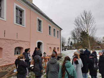 Bild der TeilnehmerInnen, die Steffi Dubrau vor einem Pücklerhaus in rosa zuhören