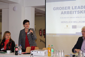 eine Rednerin und 2 Personen auf dem Podium